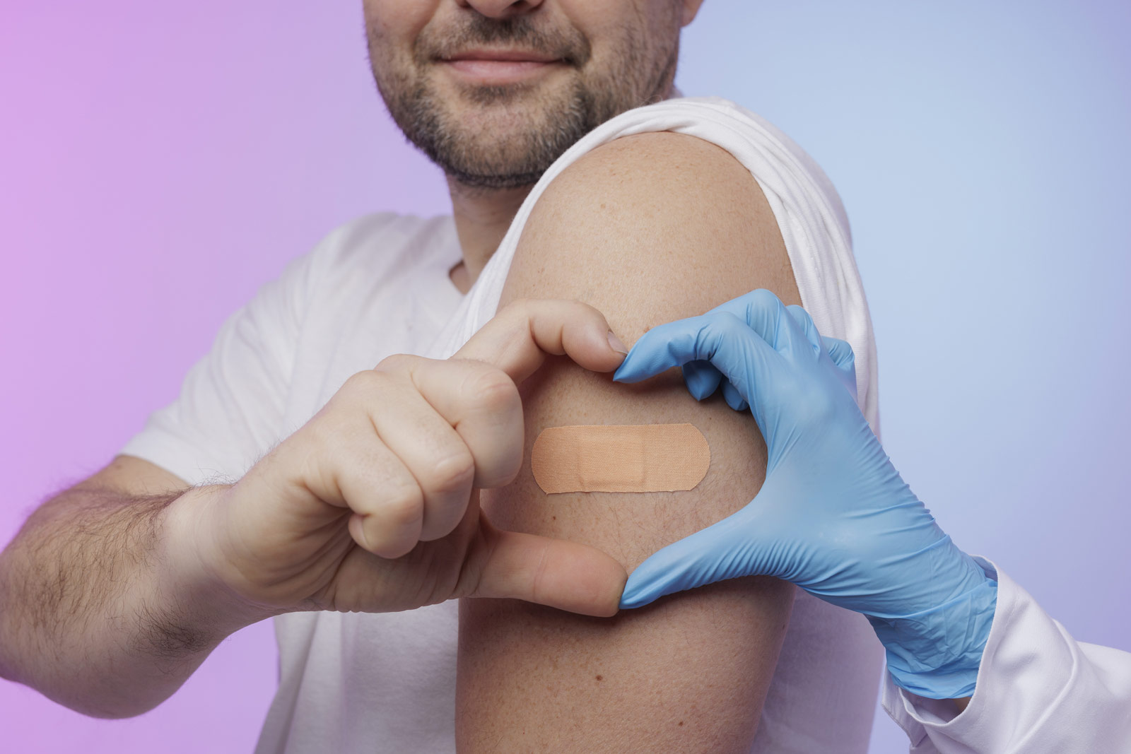 A man smiles as he forms a heart with his hands with a doctor ar